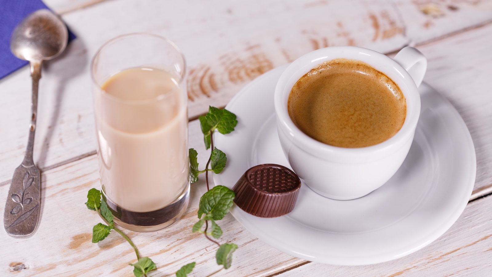 Чашка кофе с шоколадной конфетой и стаканом молока на столе