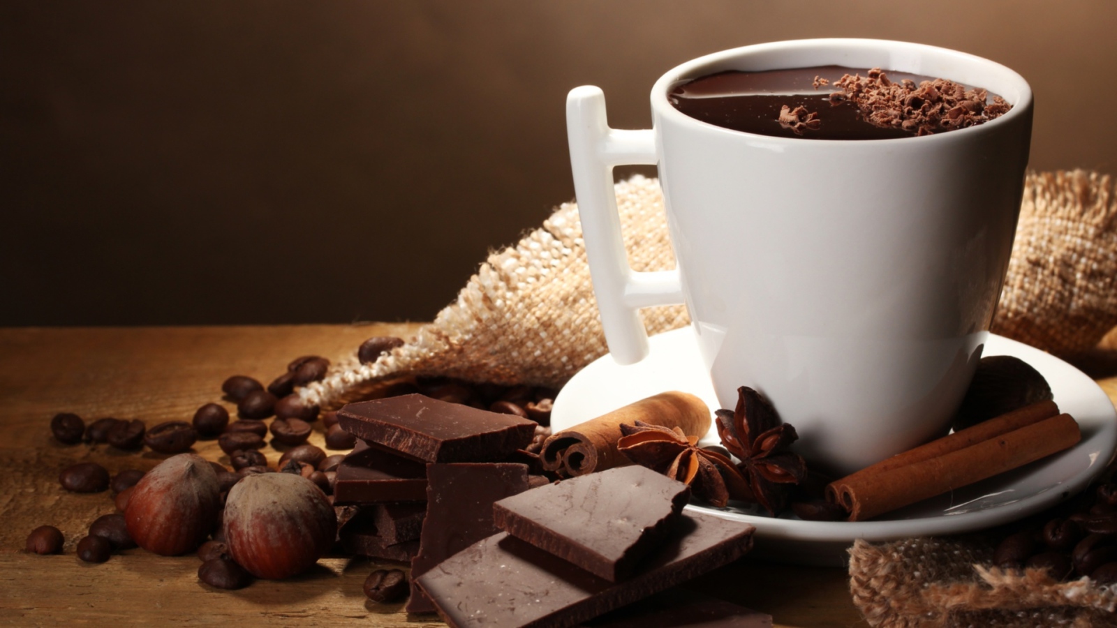 Чашка горячего шоколада на столе с корицей, бадьяном и фундуком