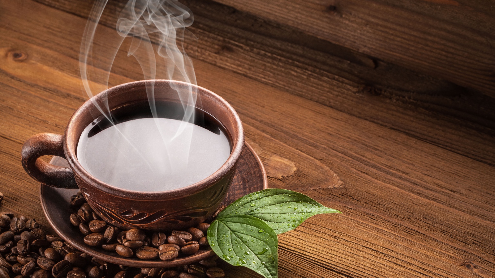 Чашка горячего кофе с зернами на деревянном столе