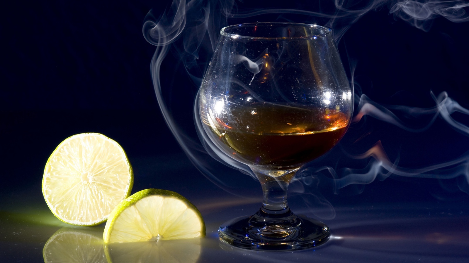 Бокал коньяка в дыму с кусочками лимона