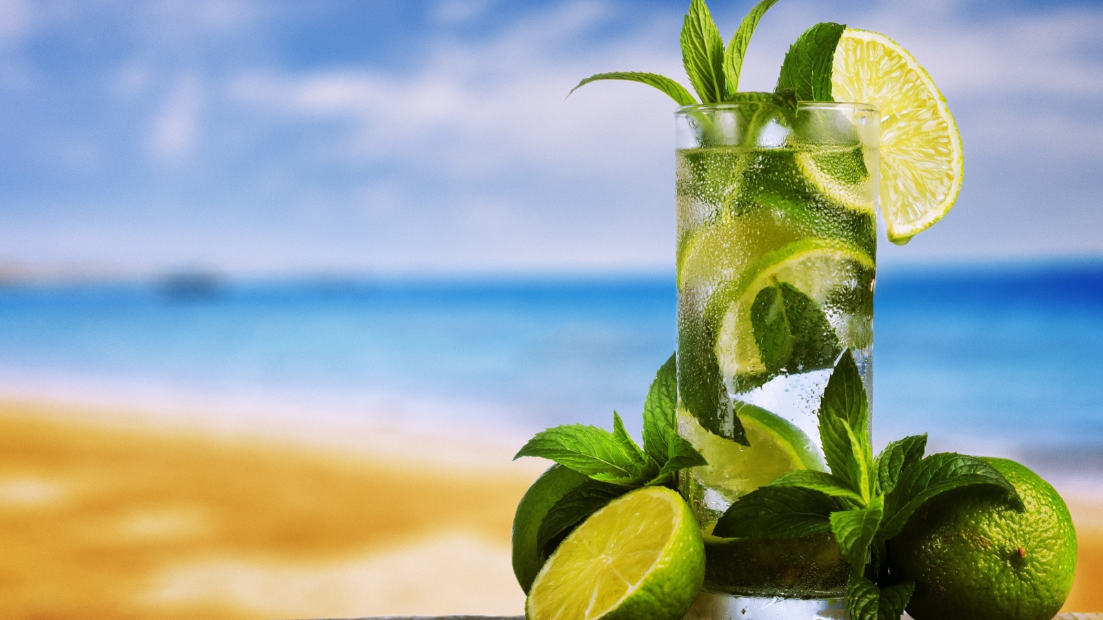 Стакан холодного мохито на столе с мятой и лаймом