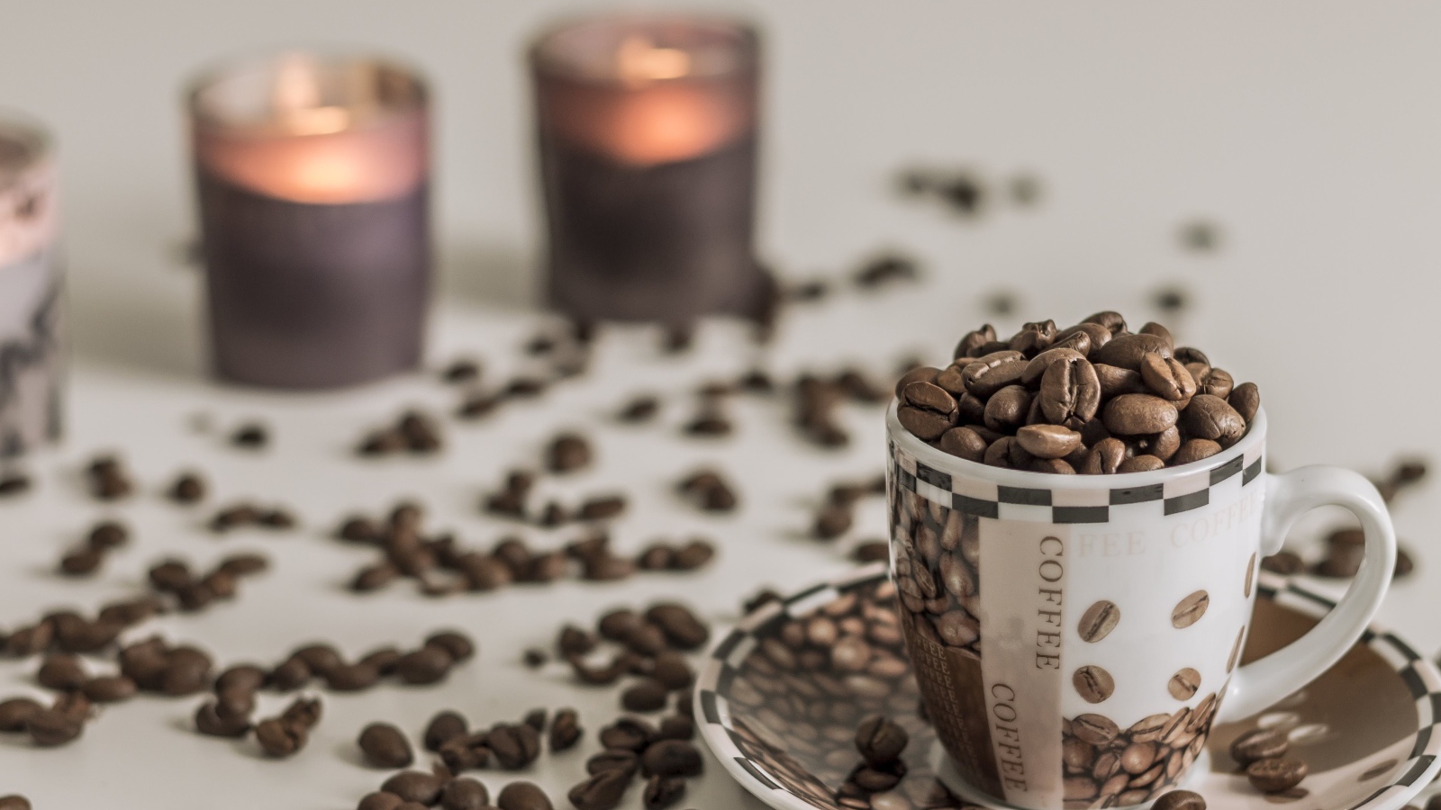 Чашка с кофейными зернами на столе со свечами