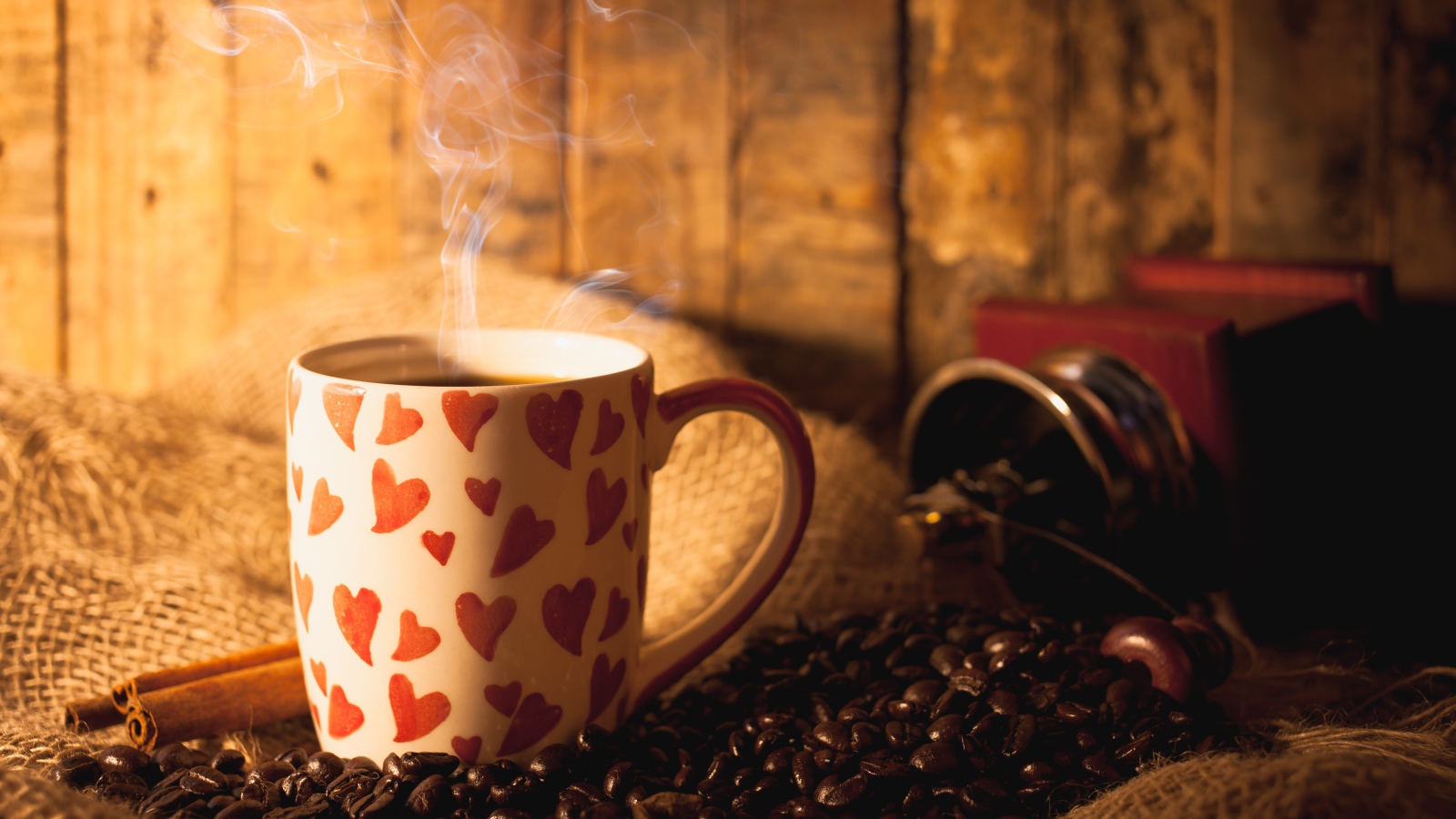 Чашка с горячим кофе на столе с кофейными зернами и корицей