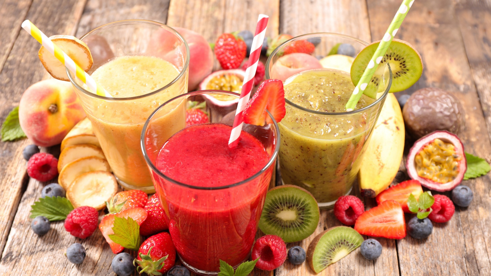 Смузи в стаканах с трубочками на столе со свежими фруктами