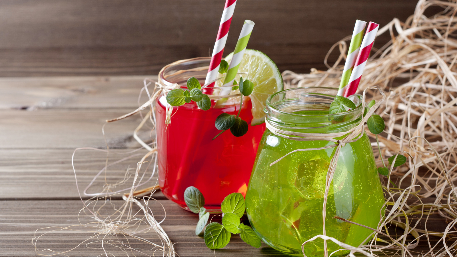 Две банки с коктейлями на деревянном столе с соломой