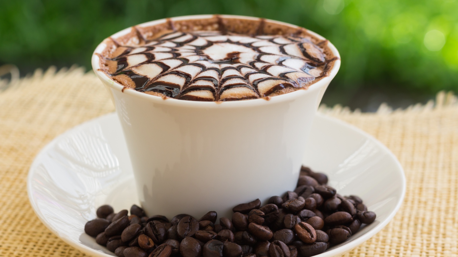 Белая чашка капучино с рисунком на пенке с кофейными зернами