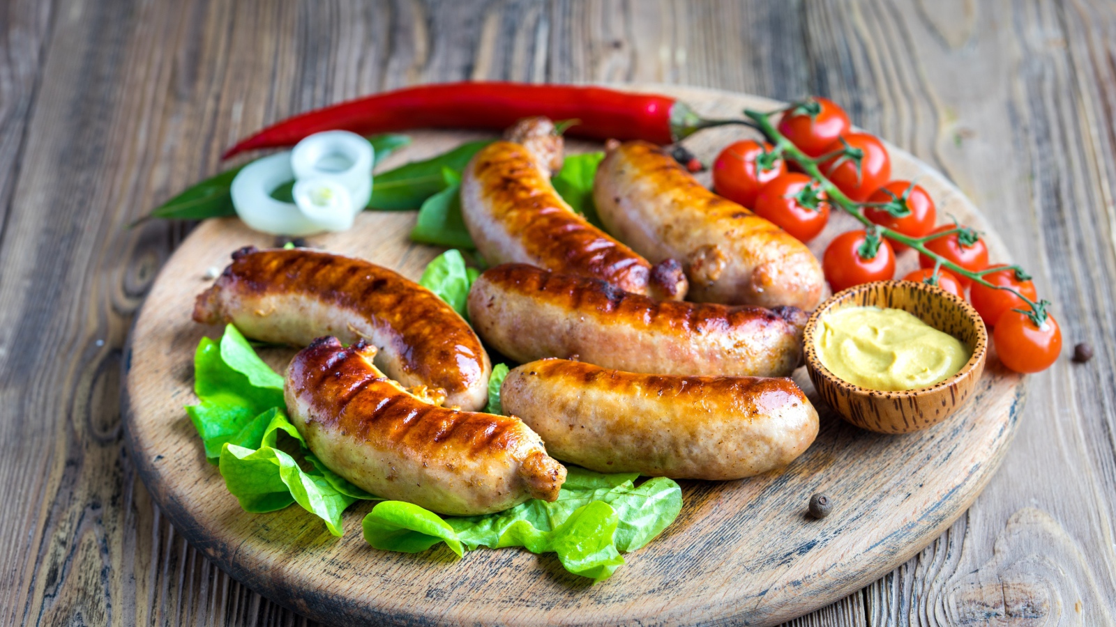 Сосиски барбекю с красным перцем и помидорами на разделочной доске