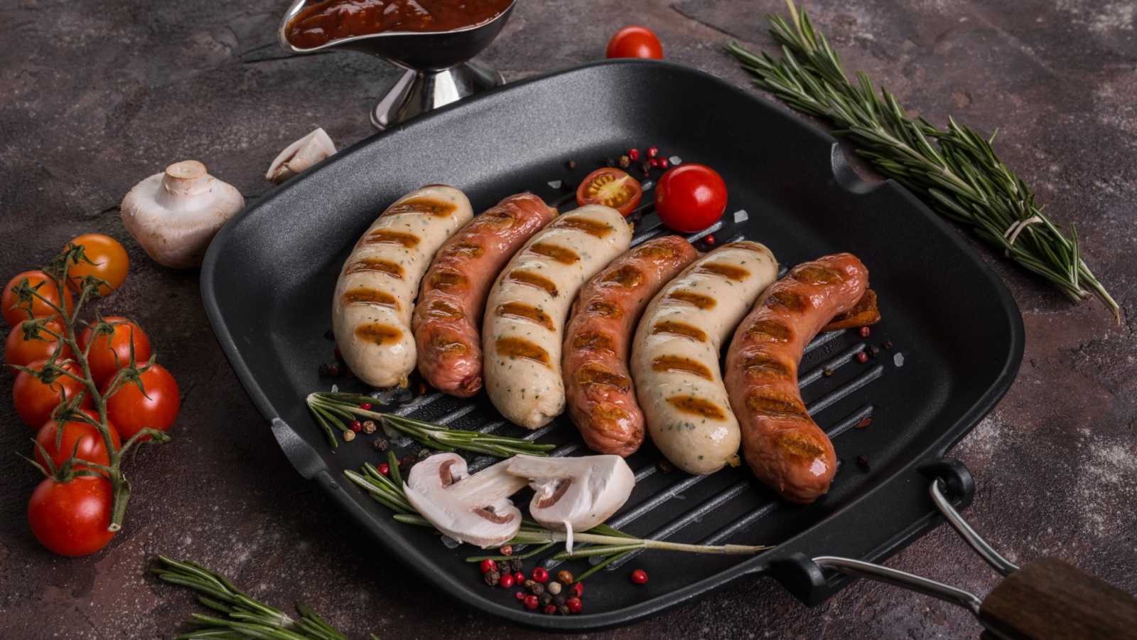 Колбаски гриль на столе с овощами 