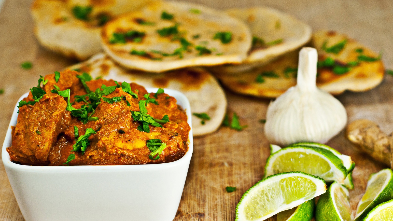 Мясное блюдо на столе с лепешками, кусочками лайма и чесноком