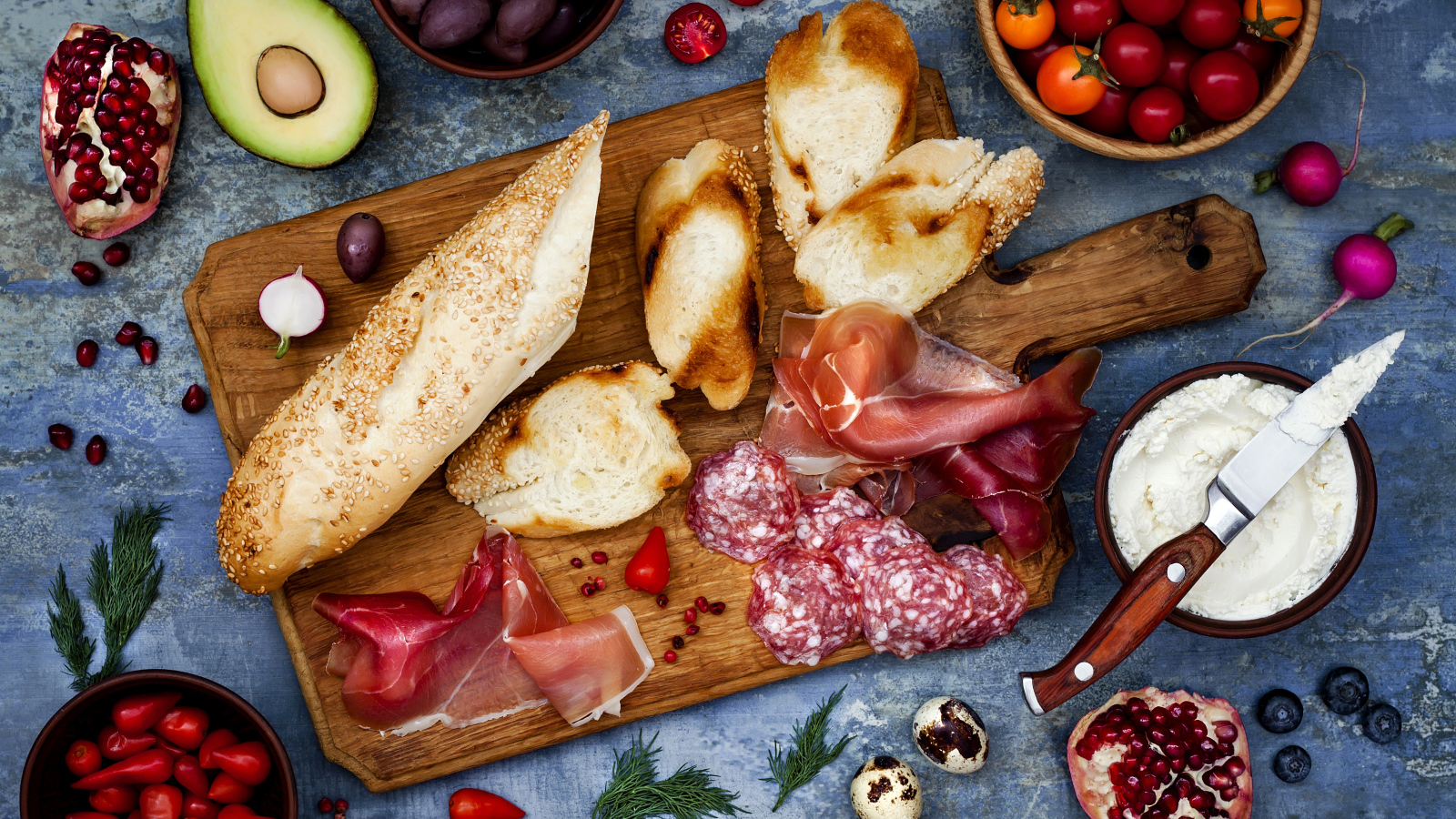 Мясные продукты с батоном и овощами на столе