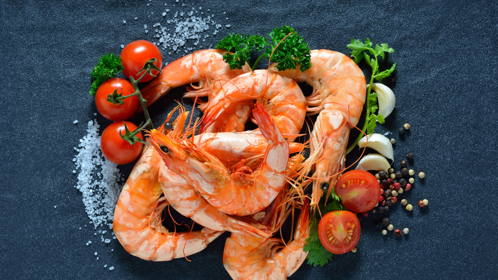 Вареные креветки на столе со специями и  помидорами 