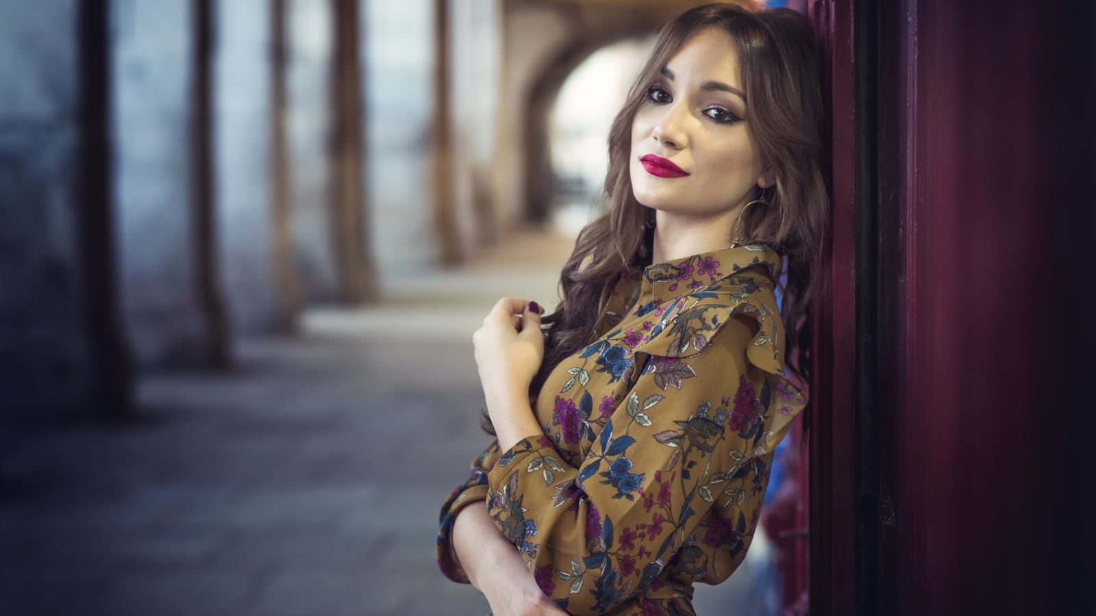 Девушка шатенка в красивом платье у стены