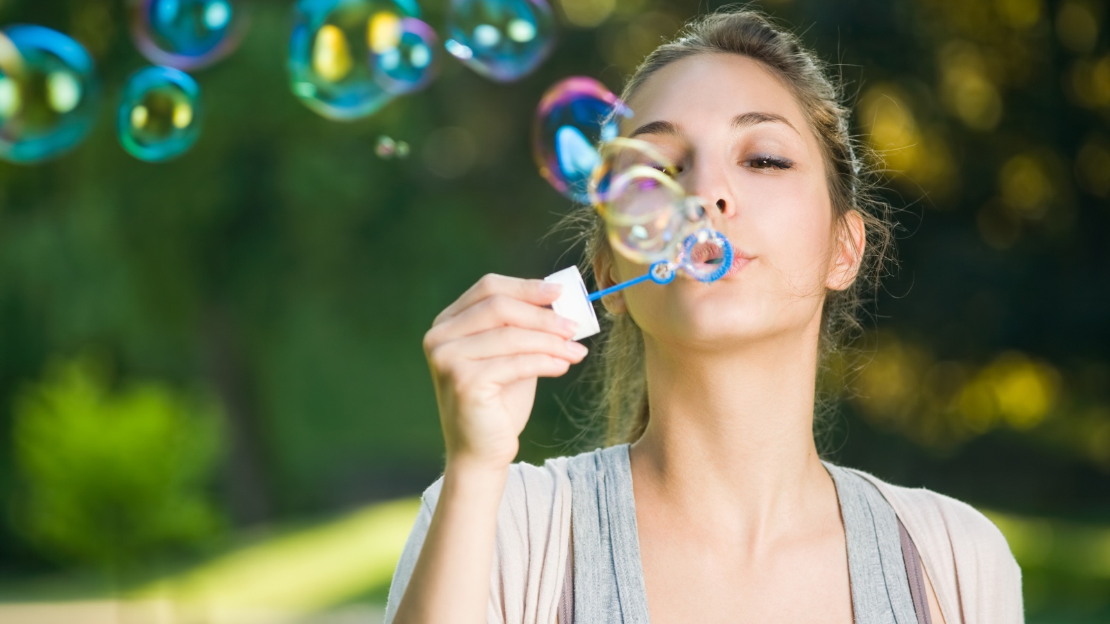 Милая молодая девушка пускает мыльные пузыри
