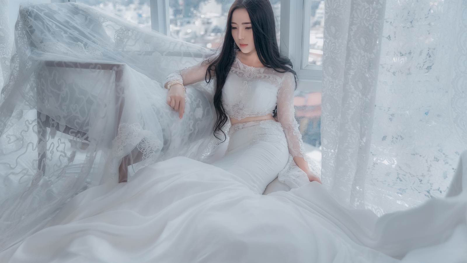 Красивая азиатка в белом свадебном платье сидит на полу