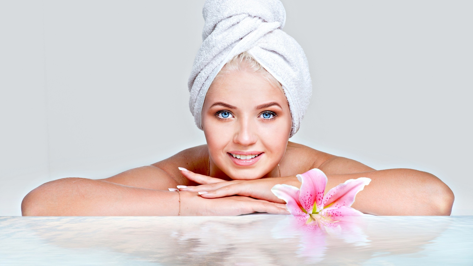 Красивая голубоглазая женщина в тюрбане с полотенца расслабляется в SPA