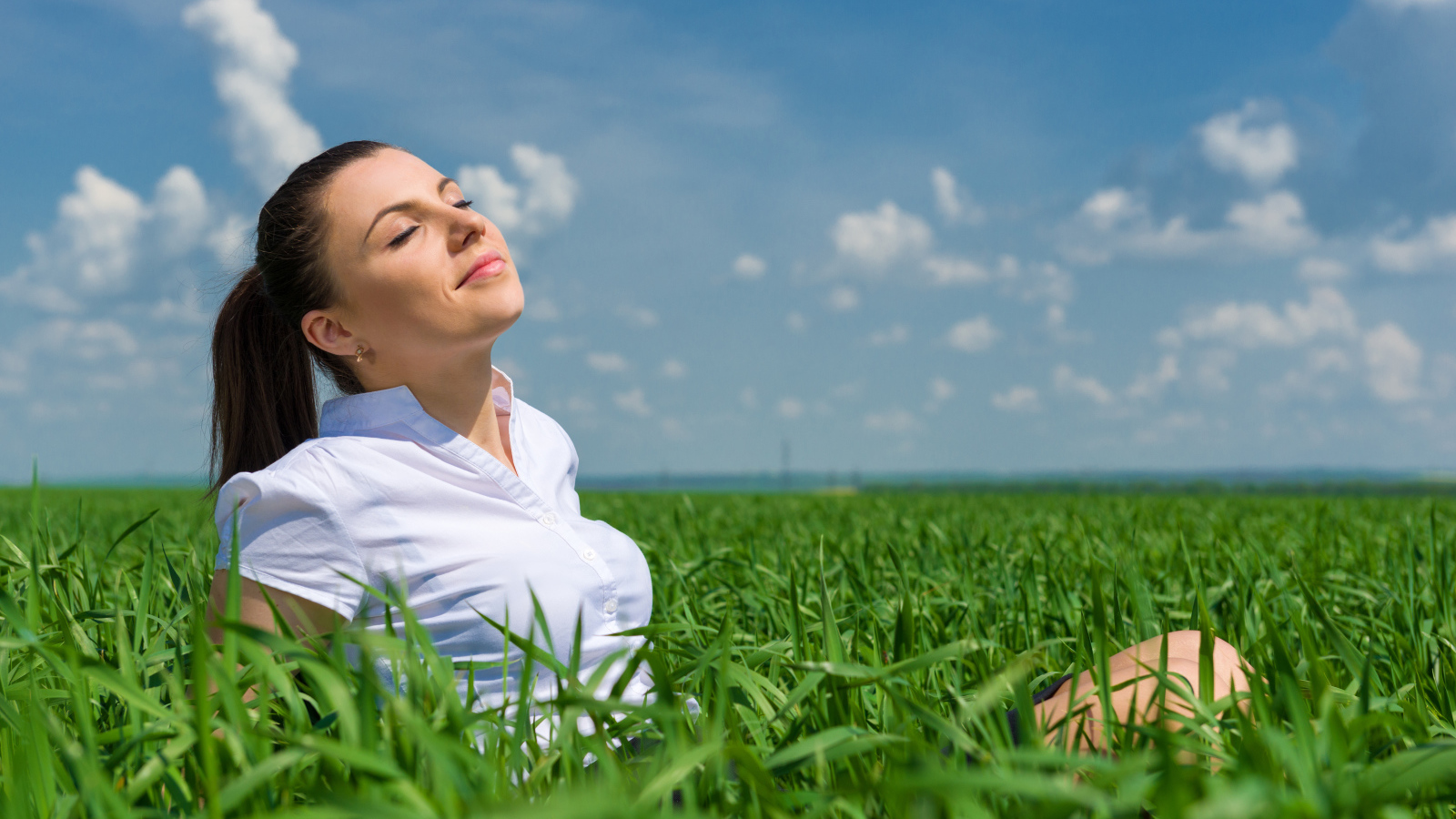 Красивая девушка нежится на солнце в зеленой траве