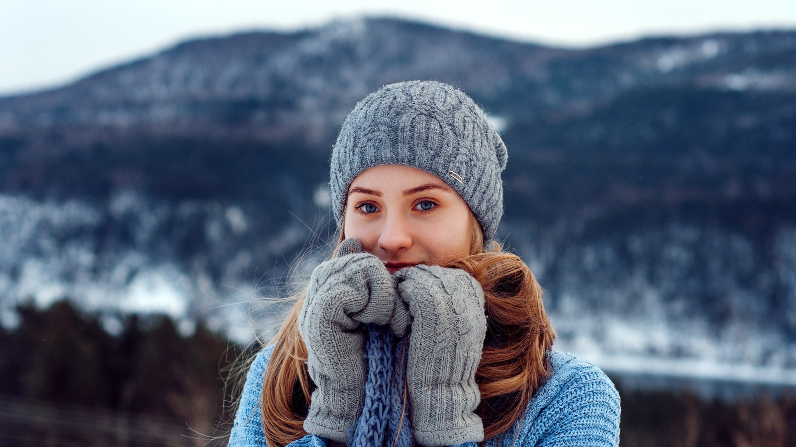 Красивая девушка в теплой шапке и варежках