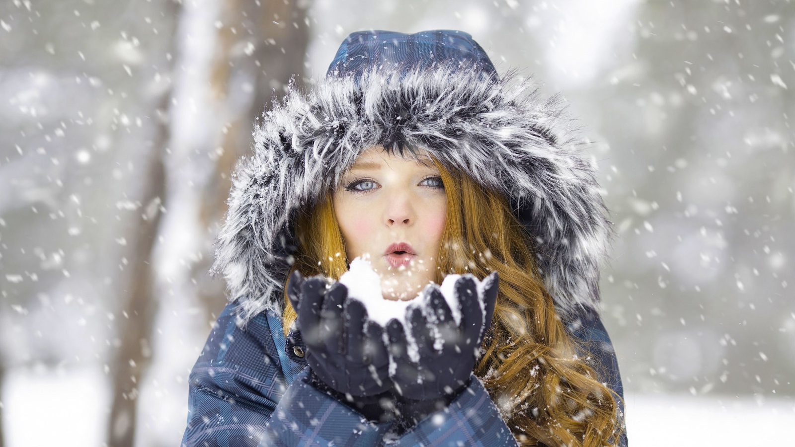 Красивая девушка в теплой куртке со снегом в руках