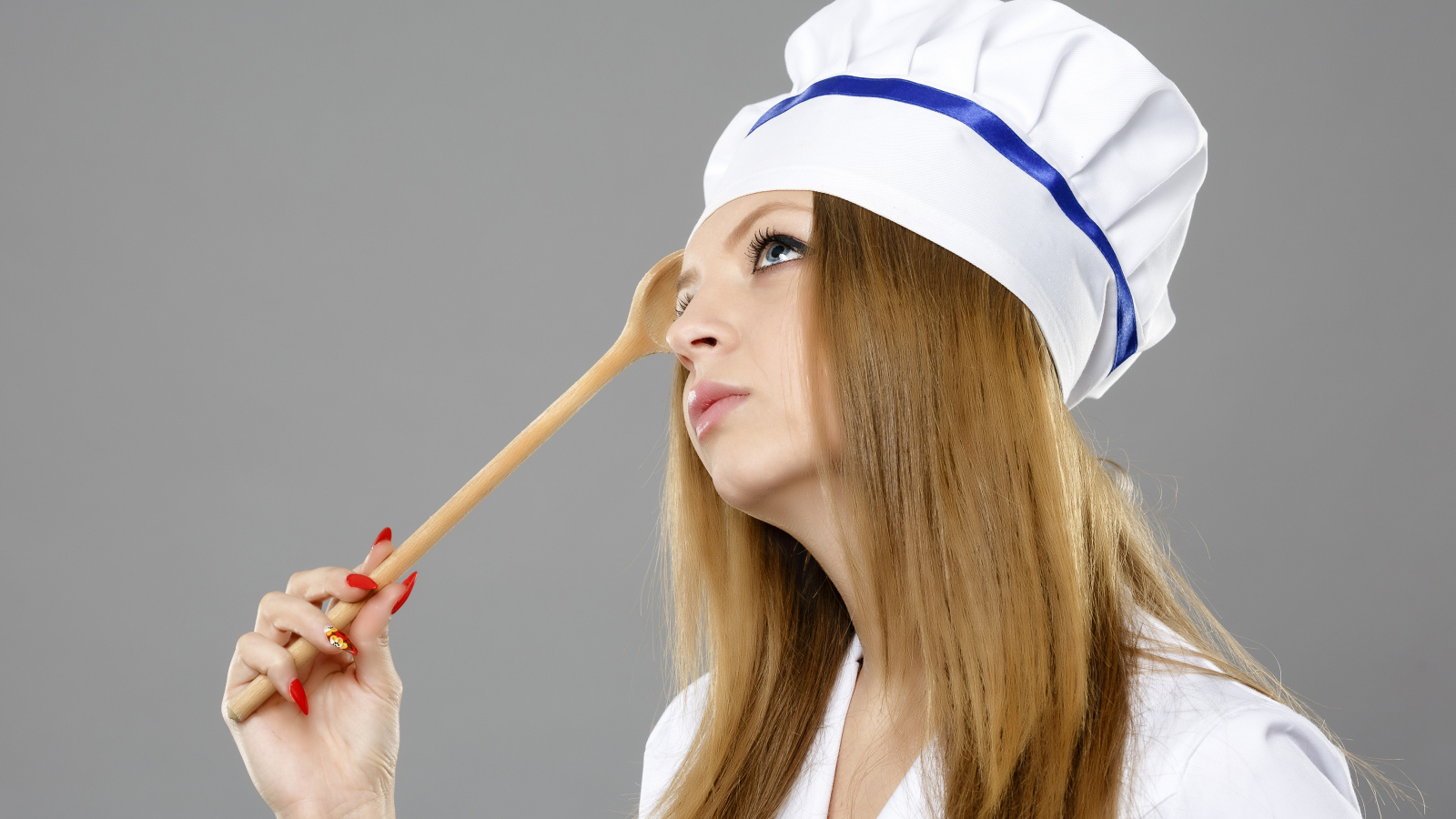 Красивая девушка в костюме повара на сером фоне