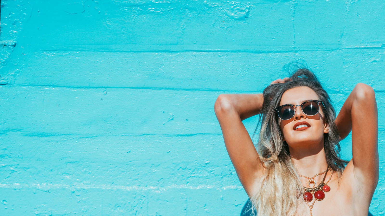 Красивая девушка в солнечных очках загорает на солнце летом