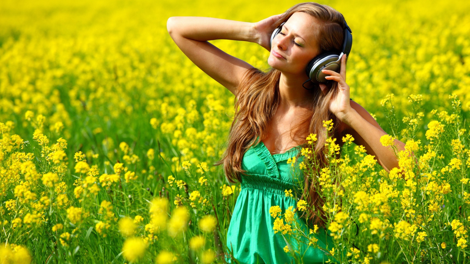 Красивая девушка в наушниках среди желтых цветов