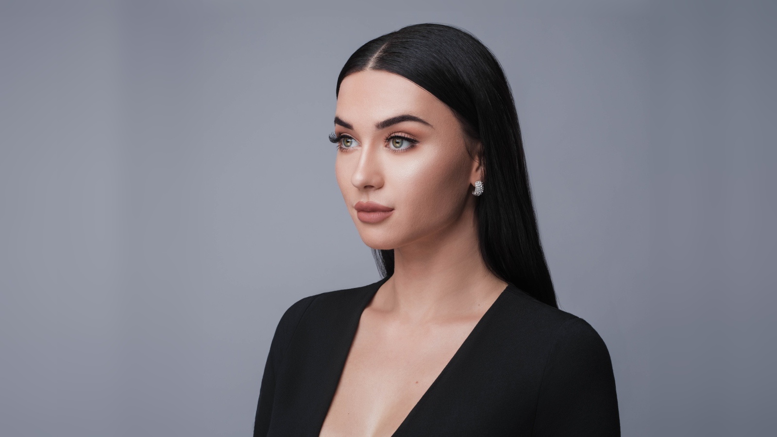 Красивая длинноволосая брюнетка в черном фото на сером фоне