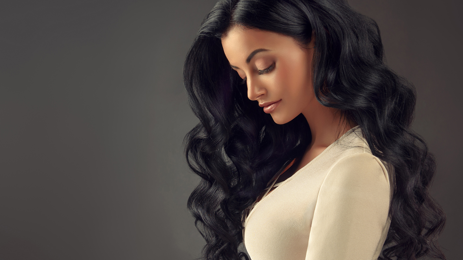 Красивая длинноволосая брюнетка на сером фоне