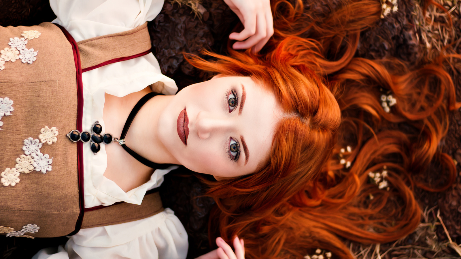 Красивая рыжеволосая девушка лежит на земле 