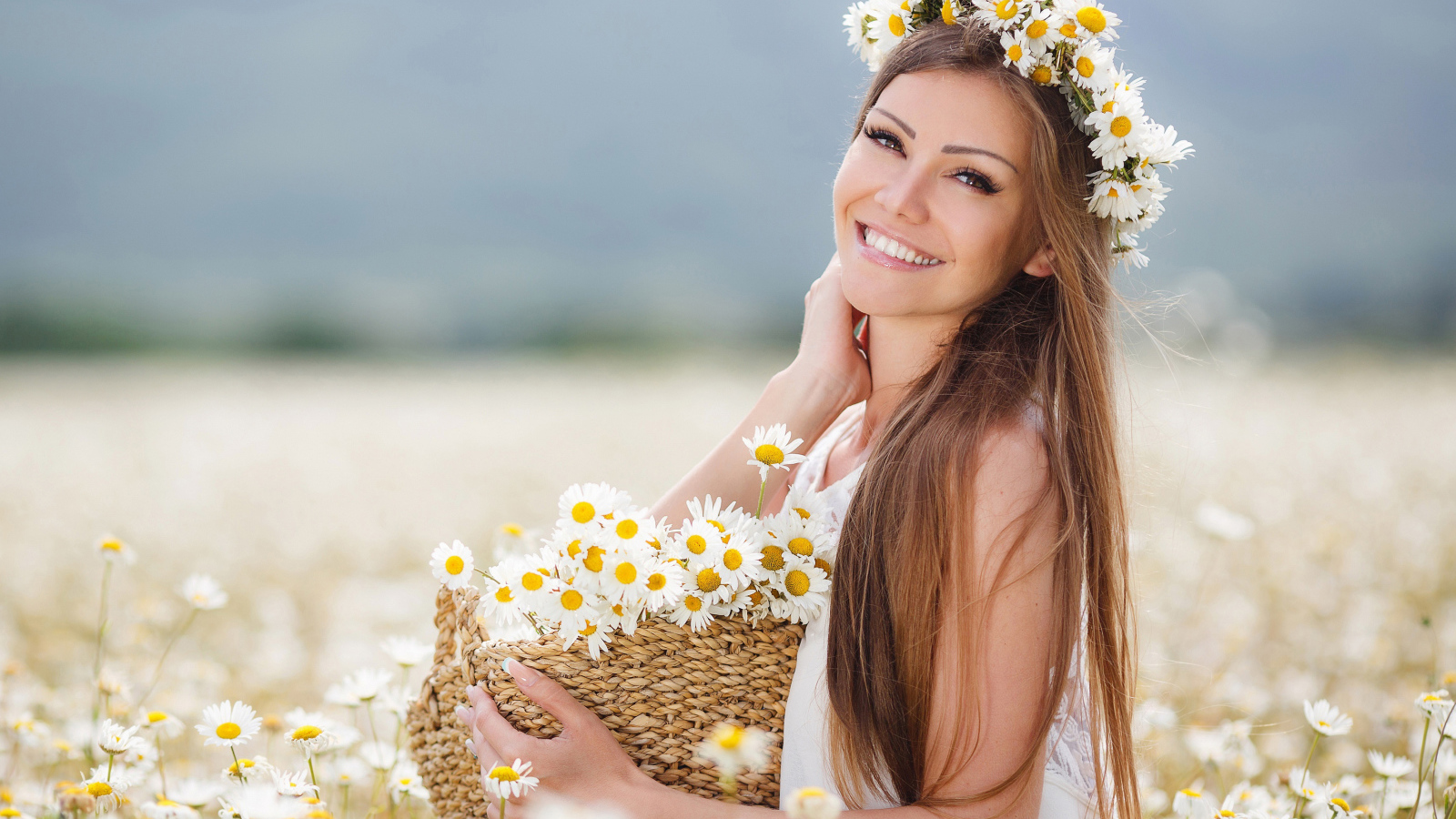 Красивая улыбающаяся девушка на поле с корзиной ромашек