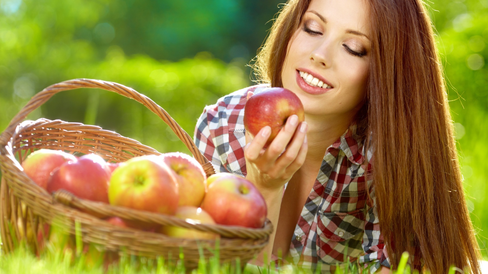 Красивая улыбающаяся девушка с корзиной красных яблок