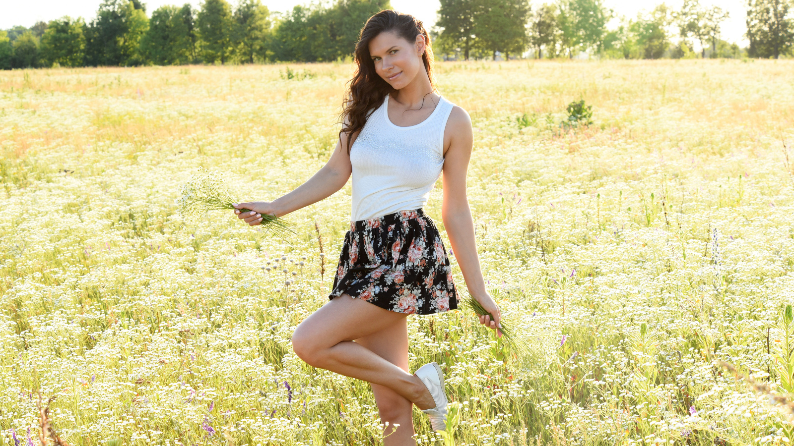 Красивая молодая девушка на поле с белыми ромашками