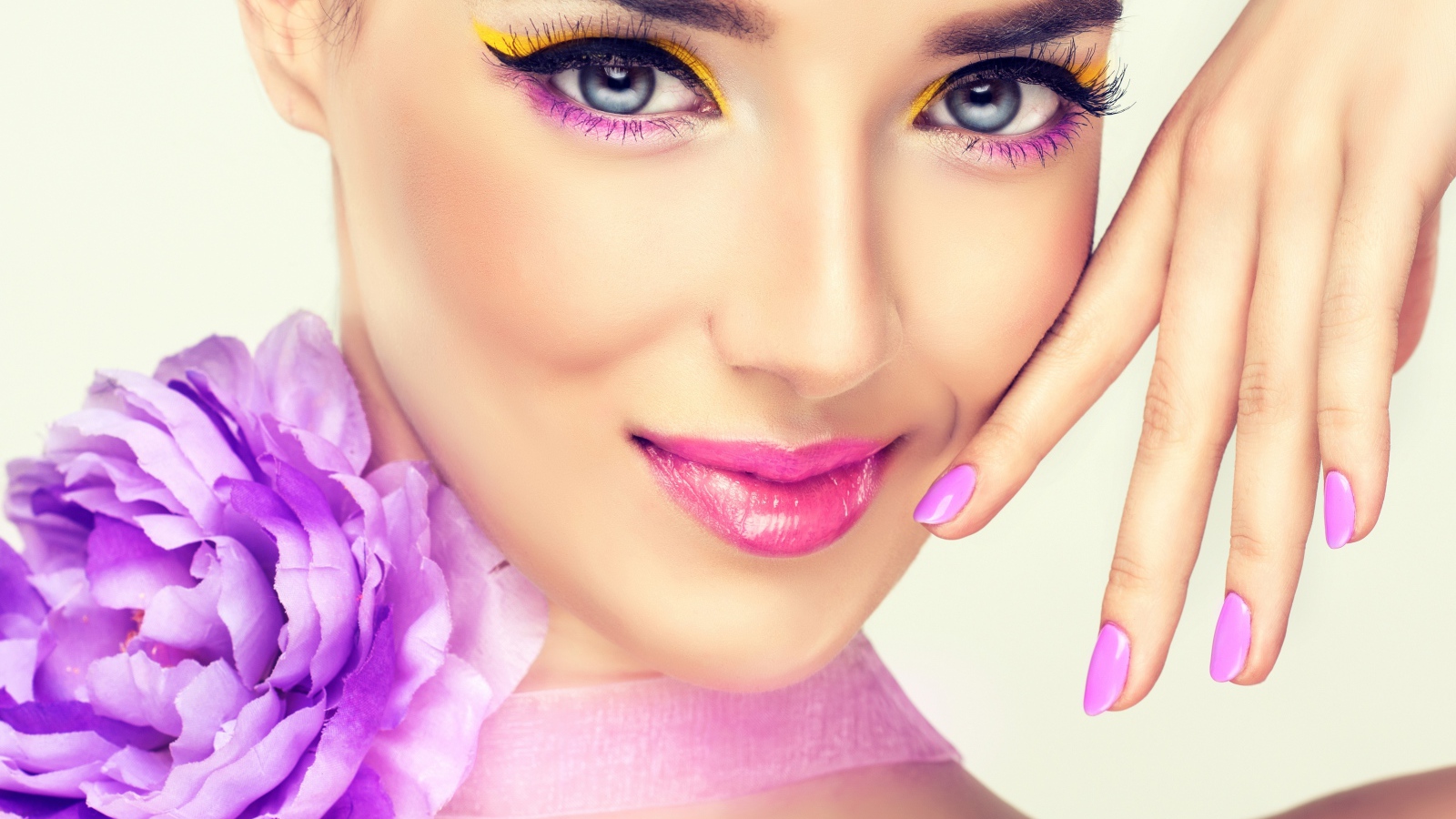 Красивая молодая девушка с ярким макияжем и сиреневым цветком на шее