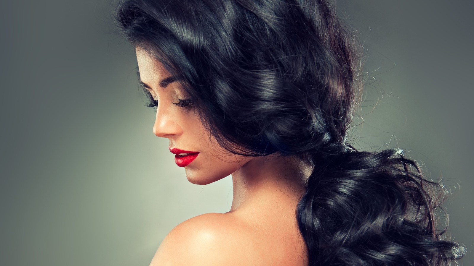 Девушка брюнетка с красивыми волосами на сером фоне
