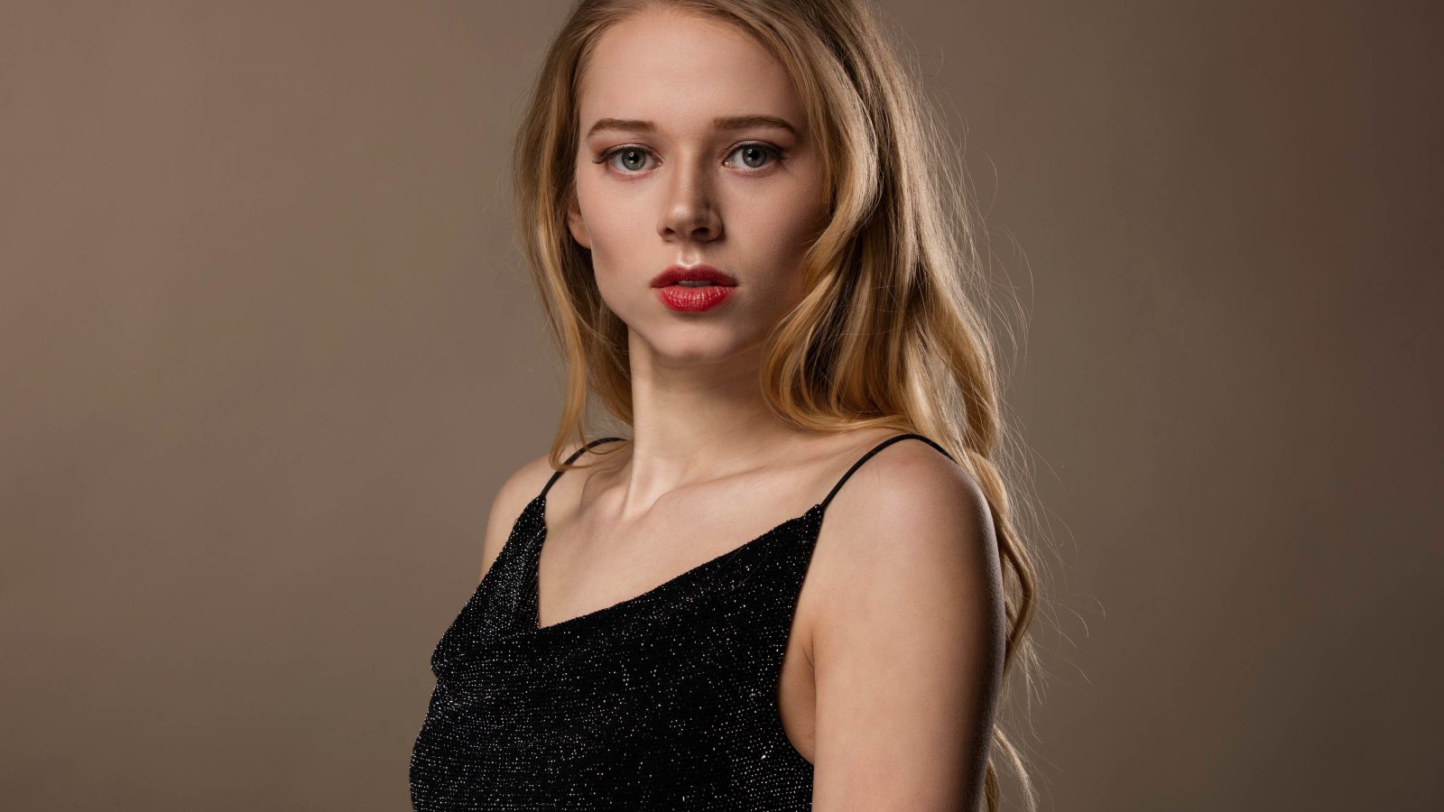 Нежная девушка модель в черном платье на сером фоне