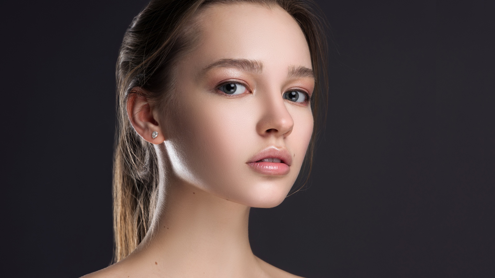 Нежная настоящая девушка шатенка на сером фоне