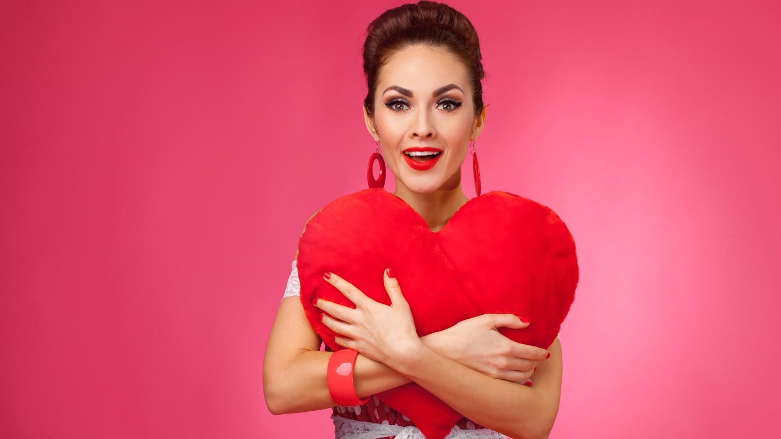 Счастливая девушка с большим красным сердцем на розовом фоне