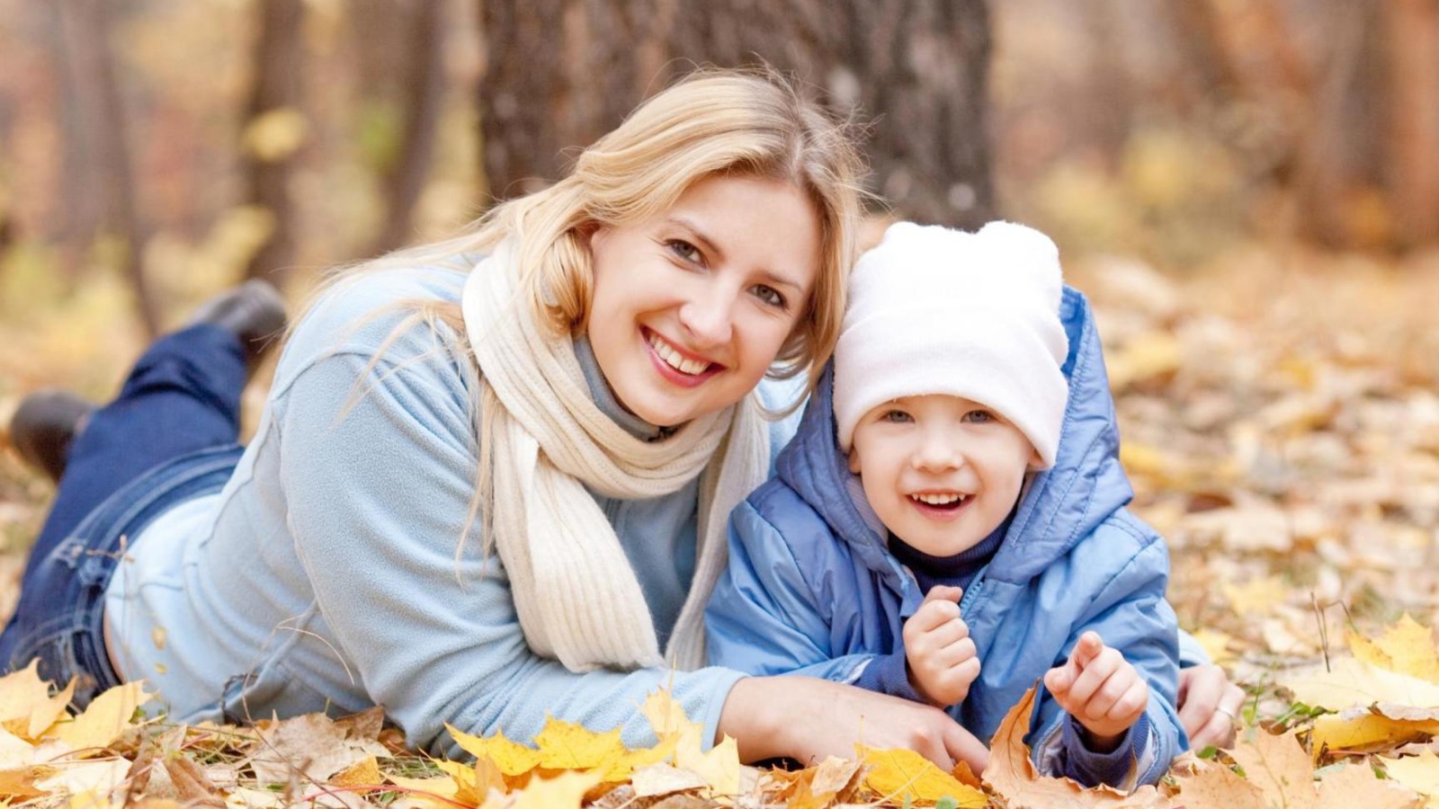 Мать с сыном лежат на листве осенью