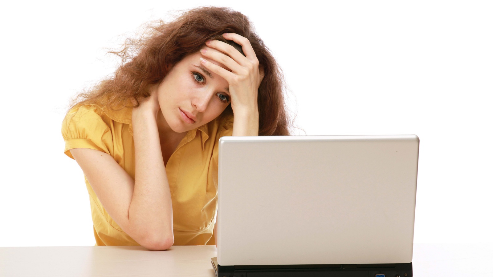 Грустная девушка сидит возле ноутбука 