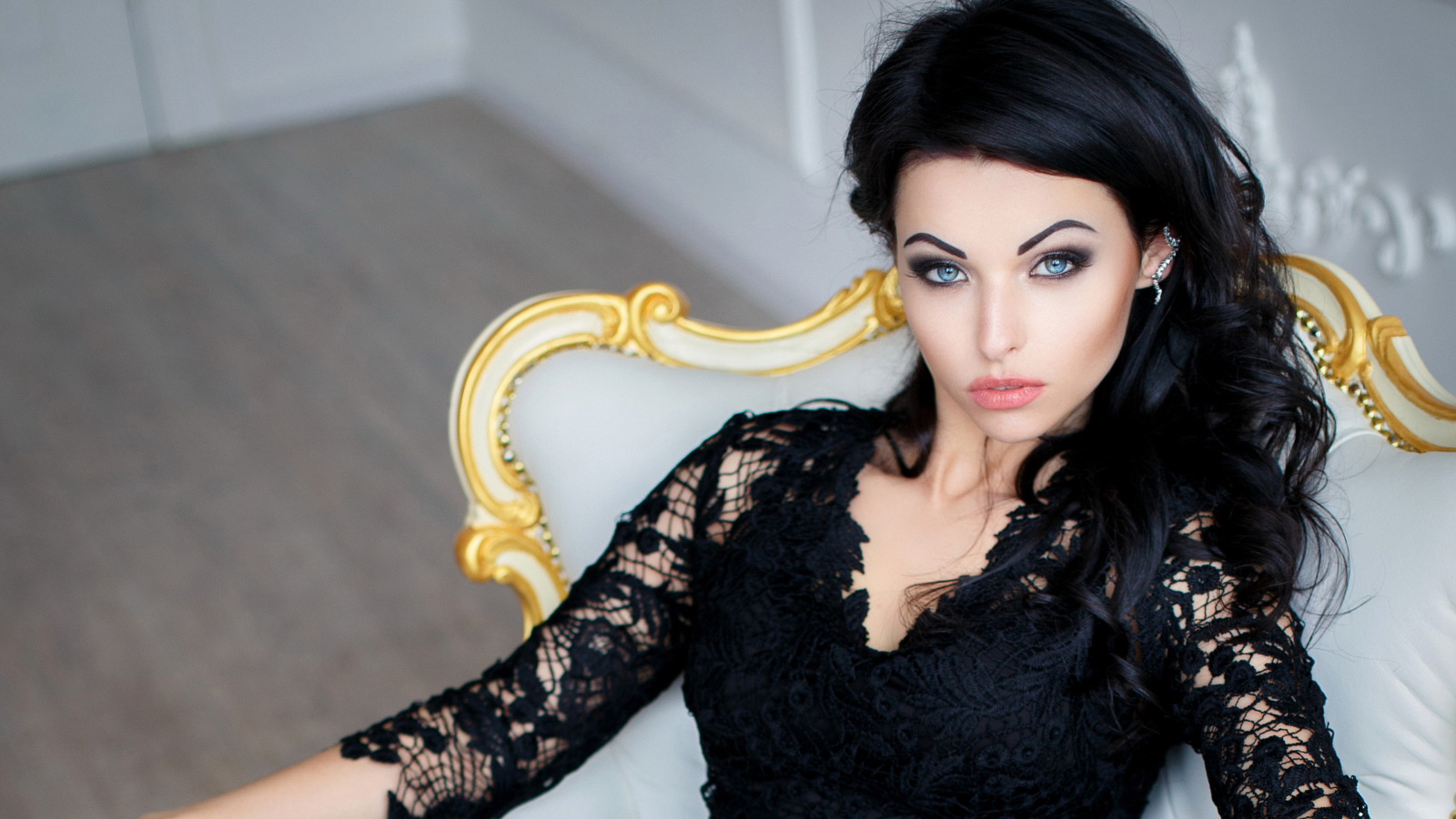 Эффектная брюнетка в черном платье сидит в кресле