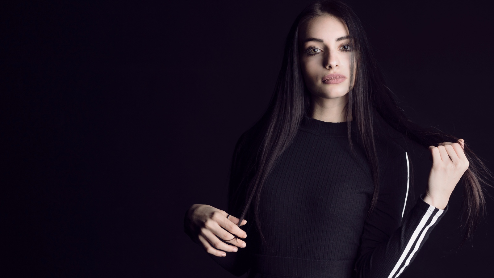 Эффектная брюнетка в черном наряде на черном фоне