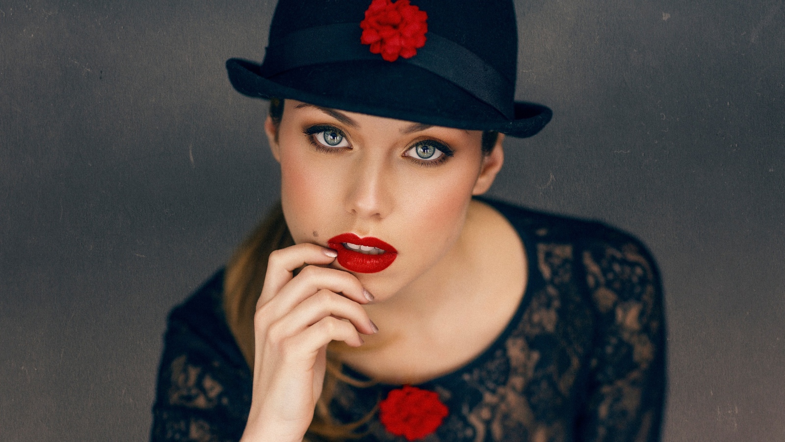 Стильная девушка с ярким макияжем в черной шляпе 