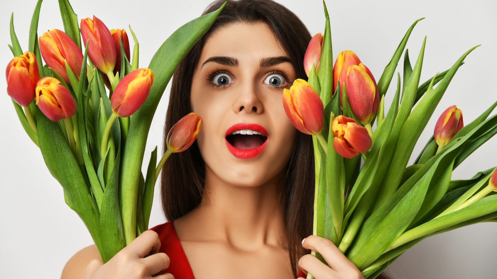 Удивленная шатенка с букетами тюльпанов