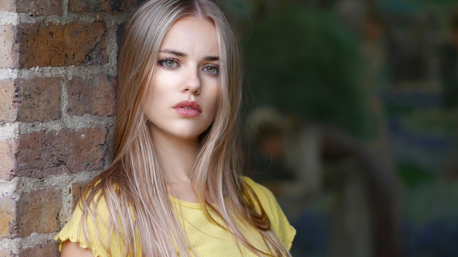 Грустный взгляд красивой светловолосой девушки у стены
