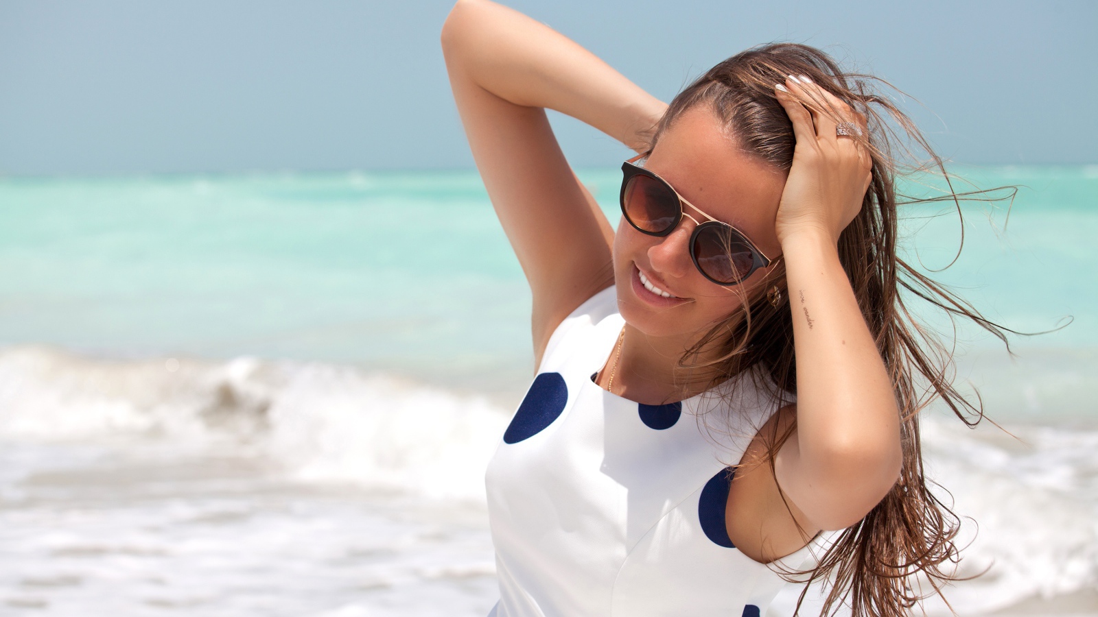 Молодая шатенка в солнечных очках у моря