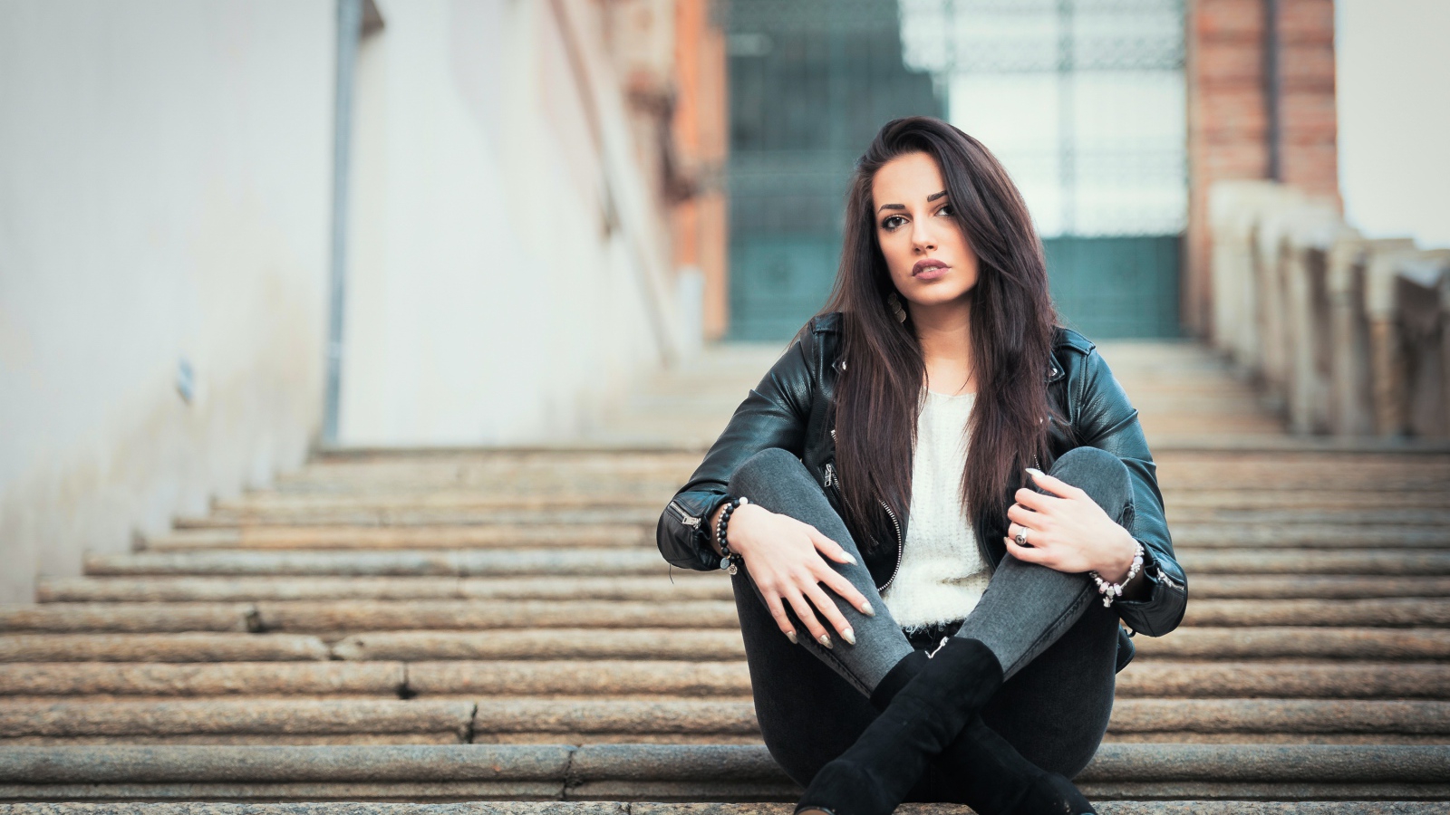 Молодая брюнетка сидит на ступеньках