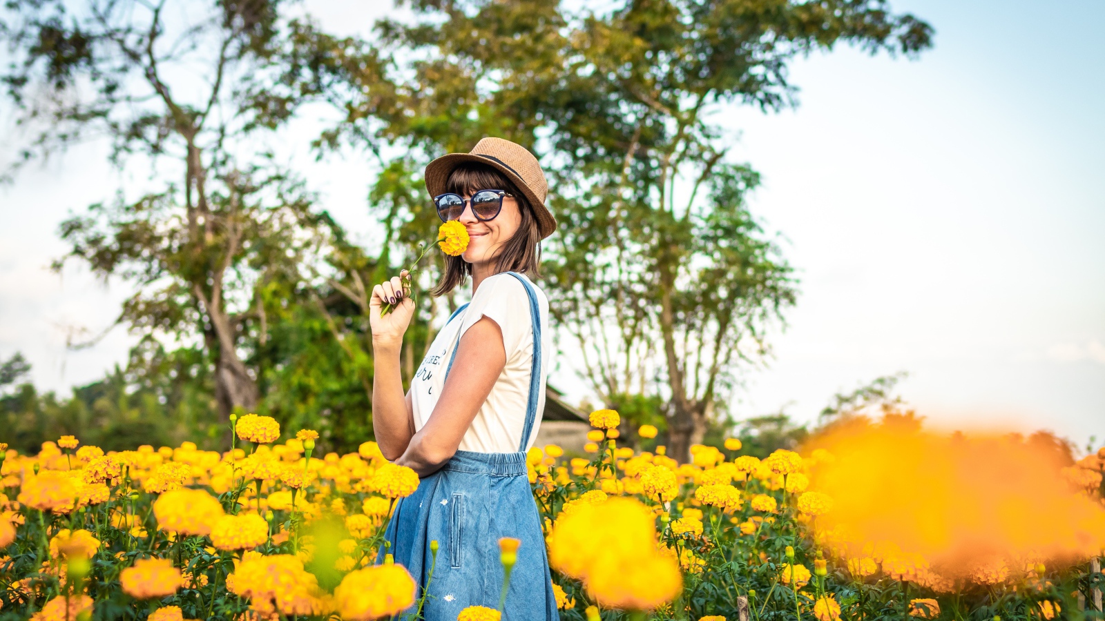 Молодая девушка в солнечных очках в желтых цветах 