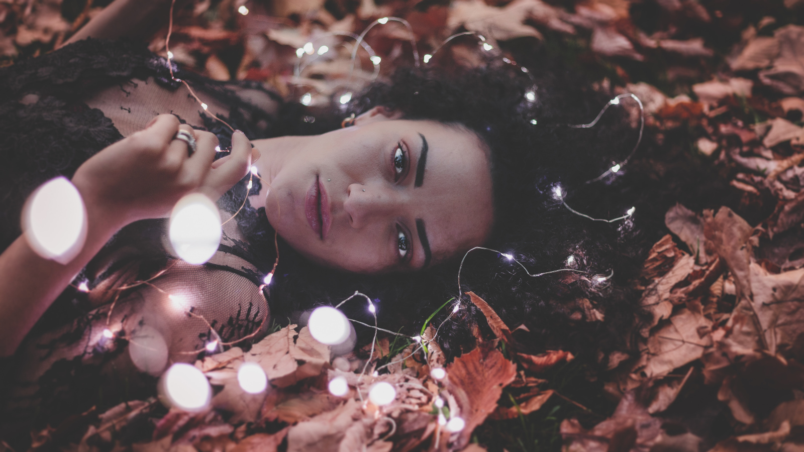 Молодая девушка лежит с гирляндой на желтых листьях