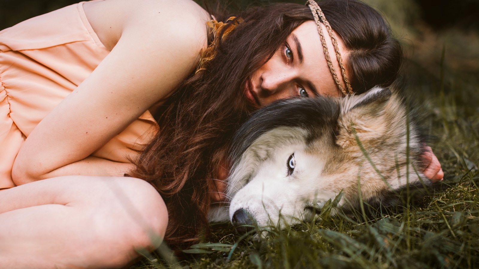 Молодая девушка с собакой породы хаски лежит на траве