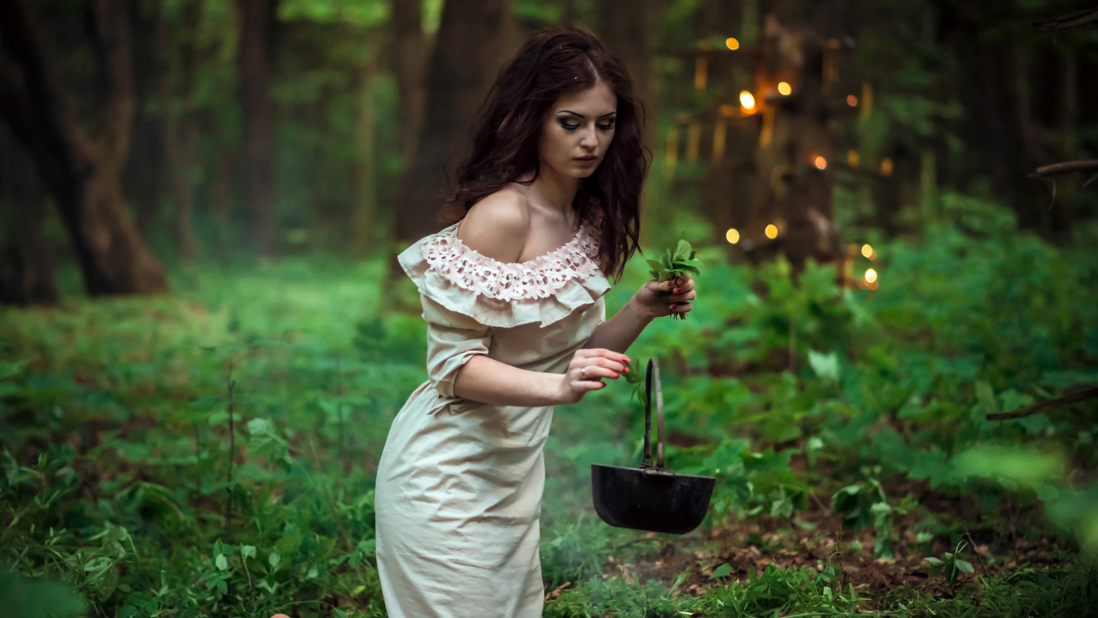 Молодая девушка колдунья варит зелье в лесу