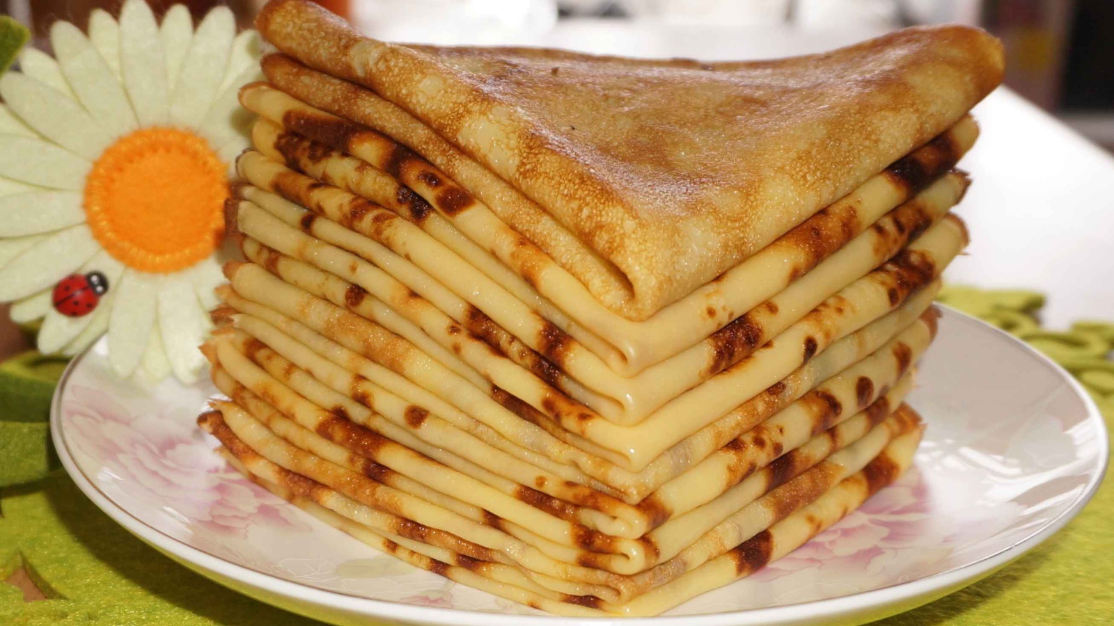 Стопка тонких блинов с ромашкой на Масленицу